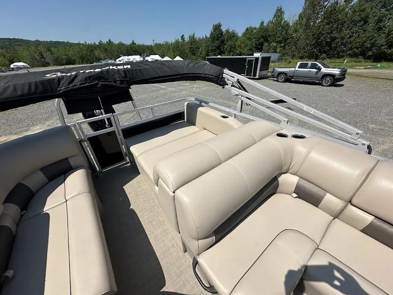 Slide: The Image of 2021 Sun Tracker PB 22 RF pontoon boat with beige seating and canopy, parked outdoors. - 7