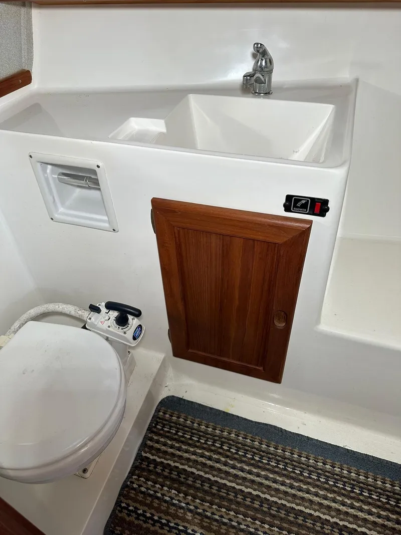 Slide: The Image of 1992 Bayliner 3288 boat bathroom with sink, toilet, wooden cabinet, and striped rug. - 20