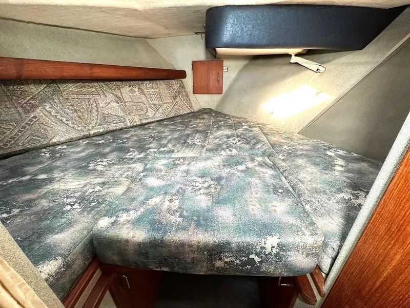 Slide: The Image of Interior cabin of a 1992 Bayliner 3288 with a patterned bed and wooden accents. - 21
