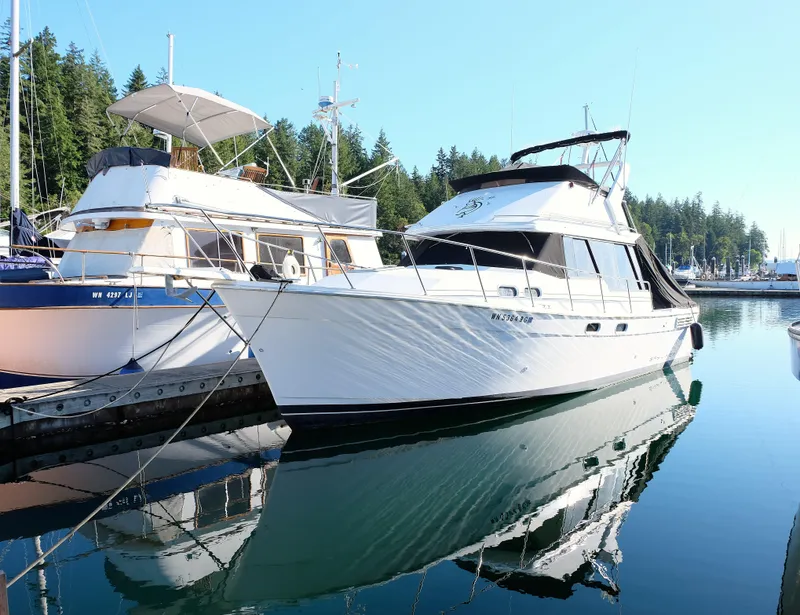 Slide: The Image of 1992 Bayliner 3288 yacht docked in a serene marina with forested background. - 30