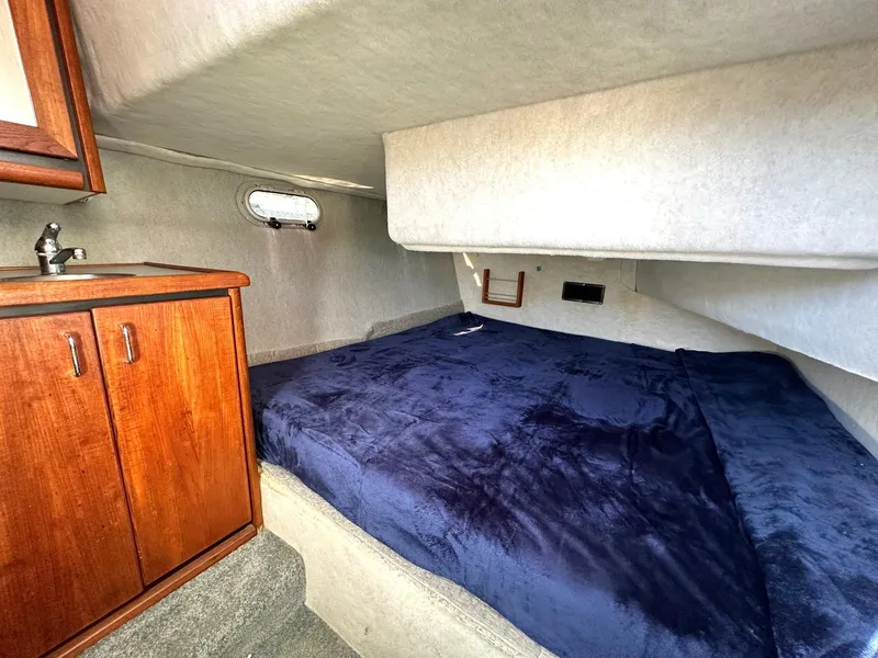 Slide: The Image of 1992 Bayliner 3288 cabin interior with bed, wooden cabinet, and small window. - 9