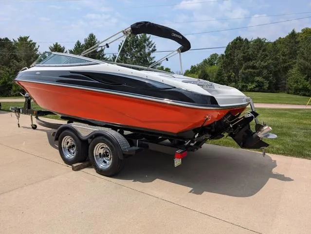 Slide: The Image of 2013 Crownline 21 SS boat on trailer, orange and black design, parked outdoors. - 4