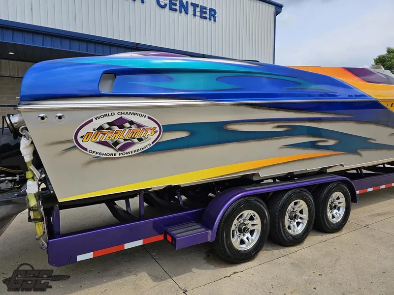 Slide: The Image of 2004 Outerlimits 42 Legacy powerboat on a triple-axle trailer outside a service center. - 13