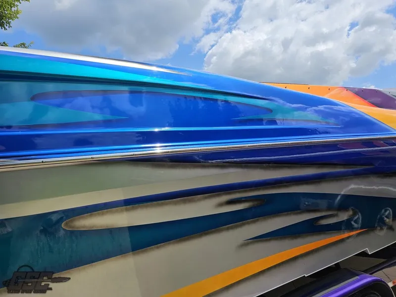 Slide: The Image of 2004 Outerlimits 42 Legacy boat with vibrant, colorful paint design under a partly cloudy sky. - 19