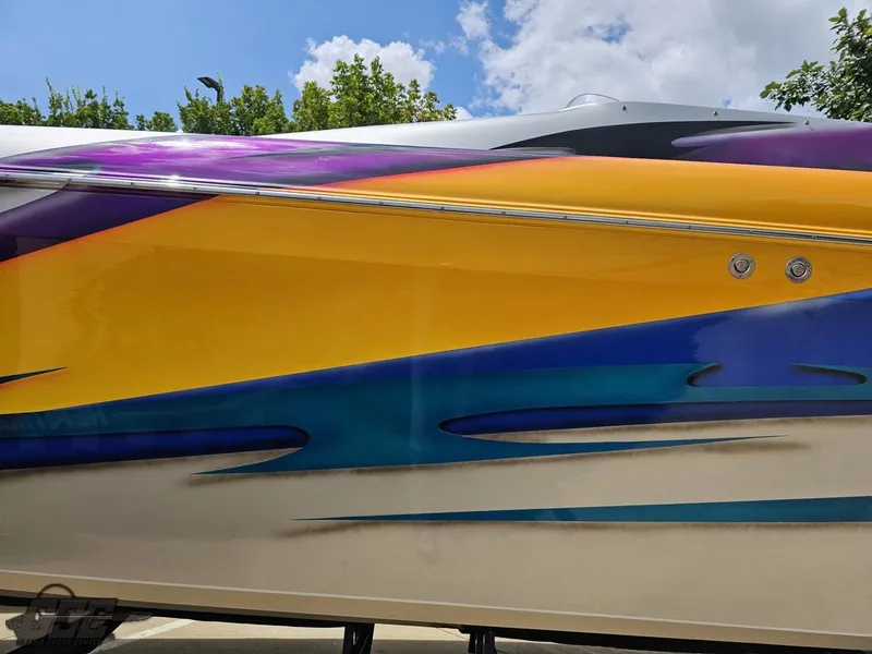 Slide: The Image of 2004 Outerlimits 42 Legacy boat with vibrant, colorful graphics against a blue sky. - 36
