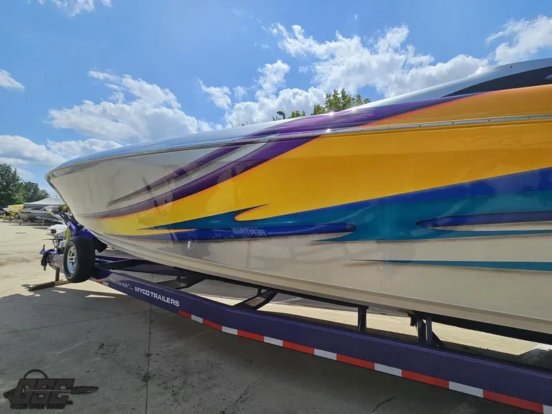 Slide: The Image of 2004 Outerlimits 42 Legacy speedboat with vibrant yellow, purple, and blue graphics on trailer. - 38