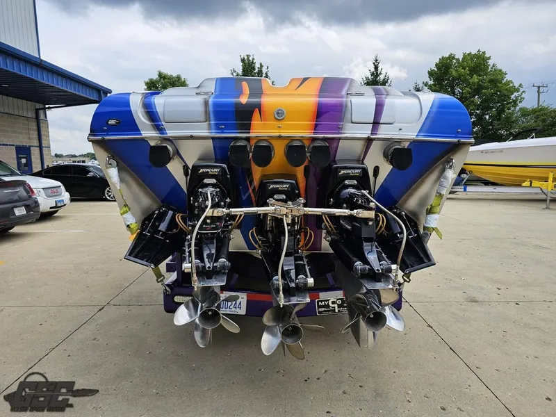 Slide: The Image of 2004 Outerlimits 42 Legacy boat with vibrant paint and powerful engines, parked outdoors. - 45