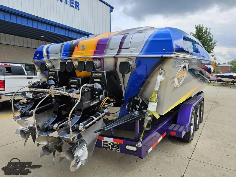 Slide: The Image of 2004 Outerlimits 42 Legacy powerboat on trailer, vibrant paint, dual engines, docked outside. - 46