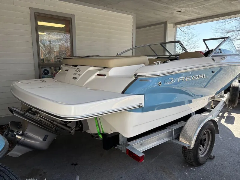 Slide: The Image of 2017 Regal 1900 ES boat on trailer, blue and white, parked under a shelter. - 14