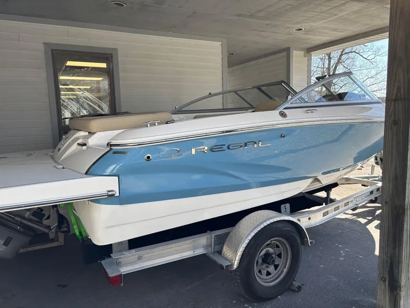 Slide: The Image of 2017 Regal 1900 ES boat on trailer, blue and white, parked under a shelter. - 15