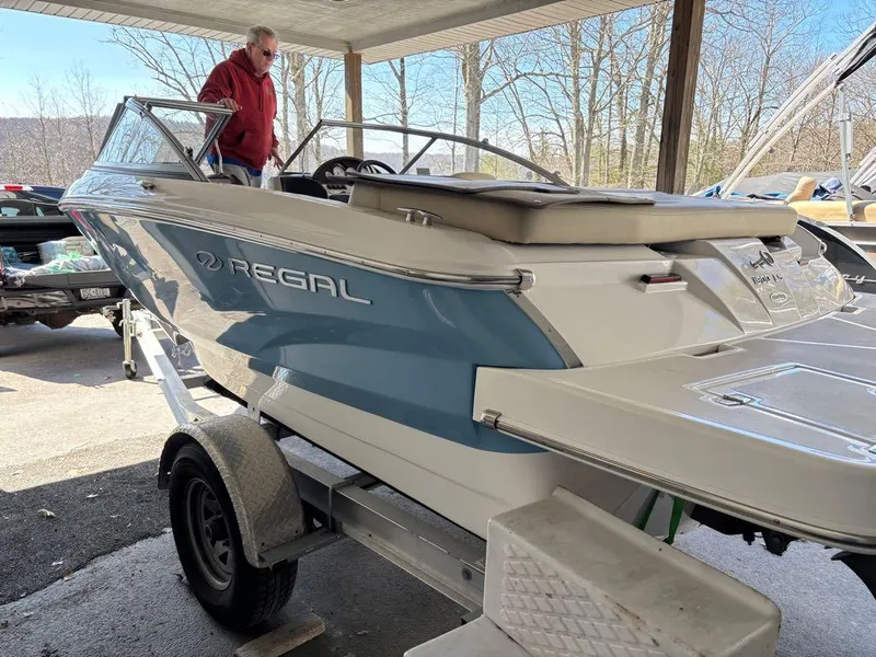 Slide: The Image of 2017 Regal 1900 ES boat on trailer under shelter, with person inspecting. - 3