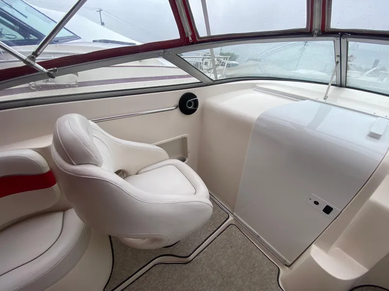 Slide: The Image of 2005 Rinker 232 Captiva Cuddy interior cockpit with white seating and red accents. - 16