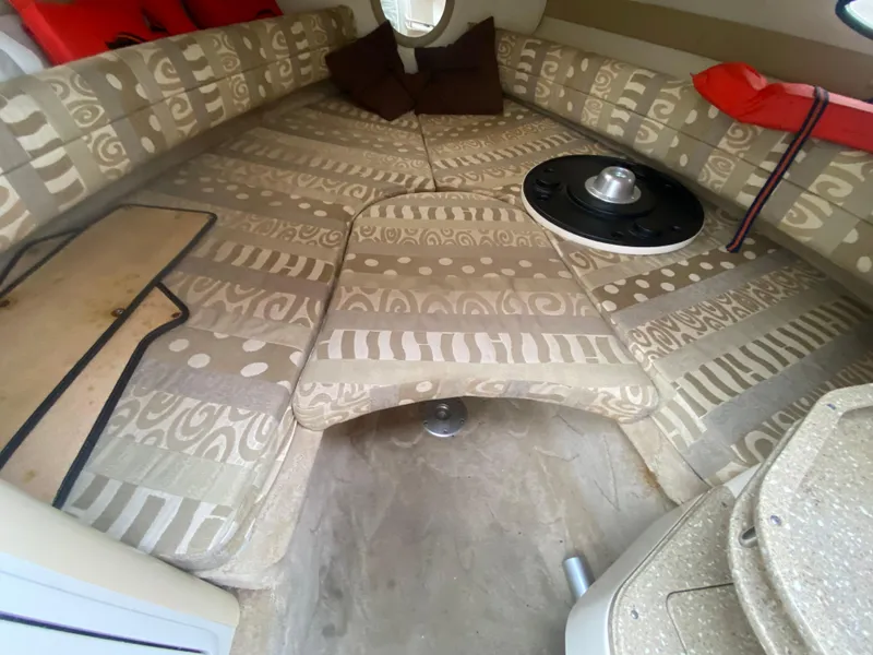 Slide: The Image of 2005 Rinker 232 Captiva Cuddy cabin interior with patterned seating and table. - 23