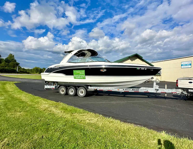 Slide: The Image of 2008 Formula 310 Bowrider on trailer, parked outdoors under a partly cloudy sky. - 0