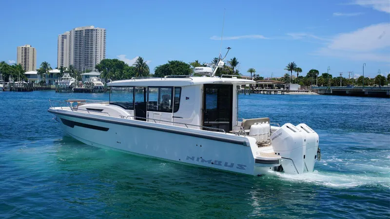 Slide: The Image of 2024 Nimbus Commuter 11 #082 boat cruising on a sunny day near a city waterfront. - 1