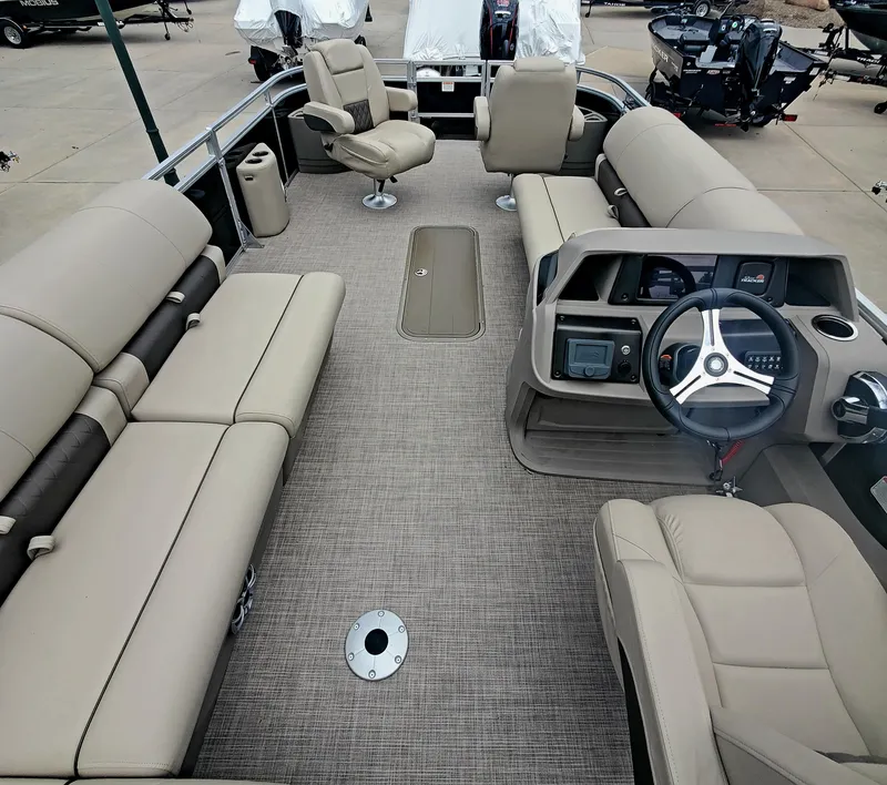 Slide: The Image of 2024 Sun Tracker Sportfish 24 XP3 pontoon boat interior with beige seating and steering console. - 2