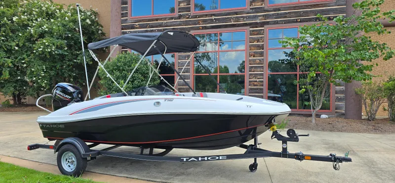 Slide: The Image of 2024 Tahoe T16 boat on trailer, parked outdoors near a building. - 2