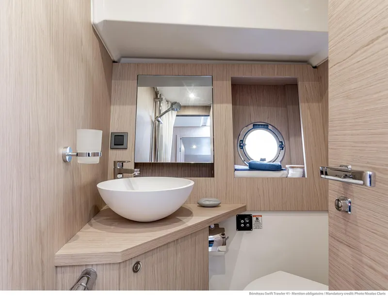 Slide: The Image of 2025 Beneteau Swift Trawler 41 Fly bathroom with modern sink and porthole window. - 15