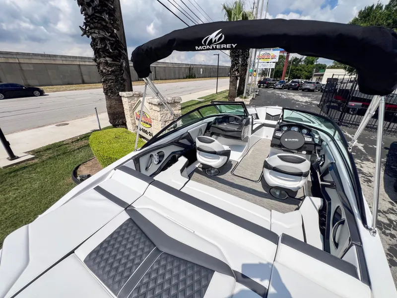 Slide: The Image of 2024 Monterey 218 SS boat with sleek interior and canopy, parked outdoors. - 19