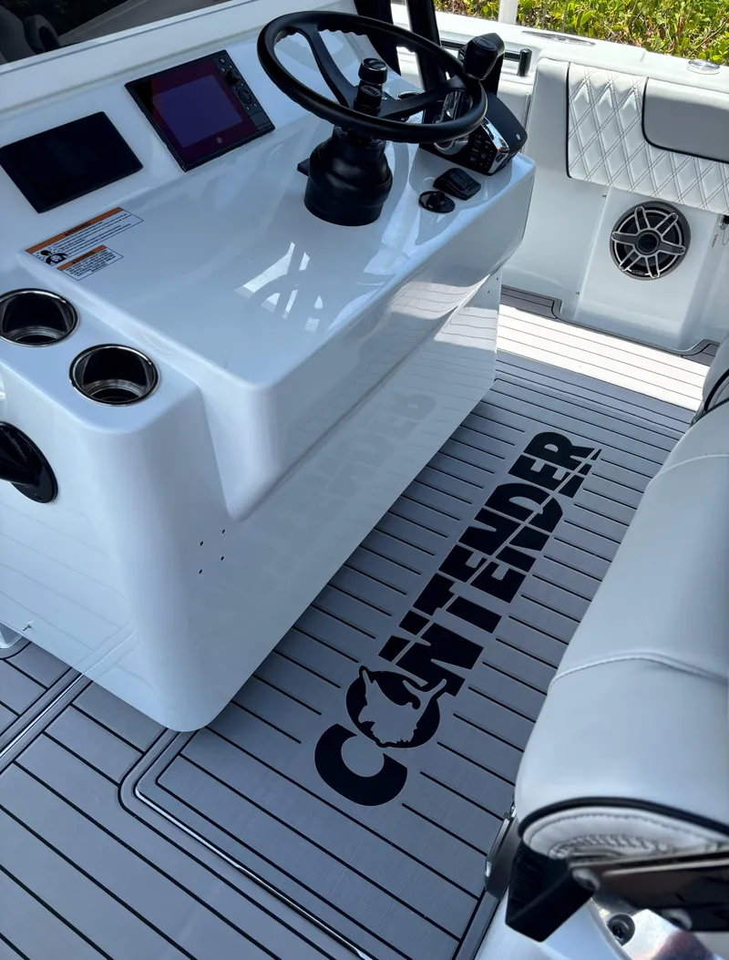 Slide: The Image of 2024 Contender 39 ST Center Console boat interior with steering wheel and branded flooring. - 17