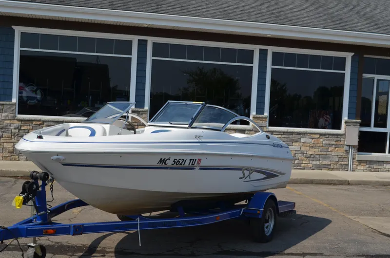 Slide: The Image of 2004 Glastron SX175 boat on a blue trailer in front of a building. - 1