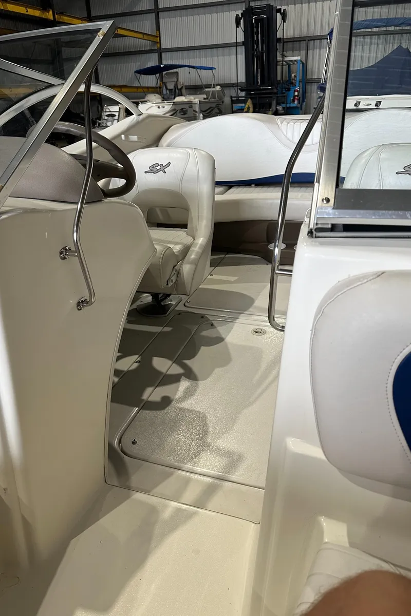 Slide: The Image of 2004 Glastron SX175 boat interior with white and blue seating in a storage facility. - 17