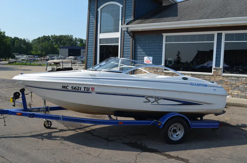 Slide: The Image of 2004 Glastron SX175 boat on a blue trailer outside a building. - 2