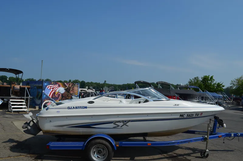 Slide: The Image of 2004 Glastron SX175 boat on a blue trailer in a marina parking lot. - 4