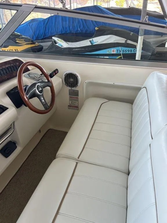 Slide: The Image of 1997 Sea Ray 330 Sundancer cockpit with white leather seating and wooden steering wheel. - 17