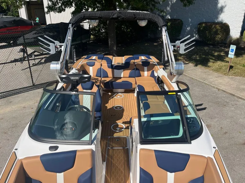 Slide: The Image of 2023 MasterCraft XT24 boat with tan and blue interior, docked outdoors. - 6