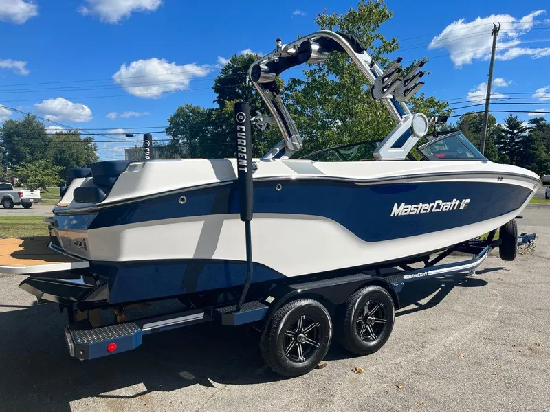 Slide: The Image of 2023 MasterCraft XT24 boat on a trailer under a clear blue sky. - 7