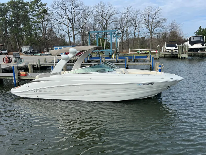 Slide: The Image of 2016 Crownline 270 SS boat docked at a marina, surrounded by trees and water. - 0