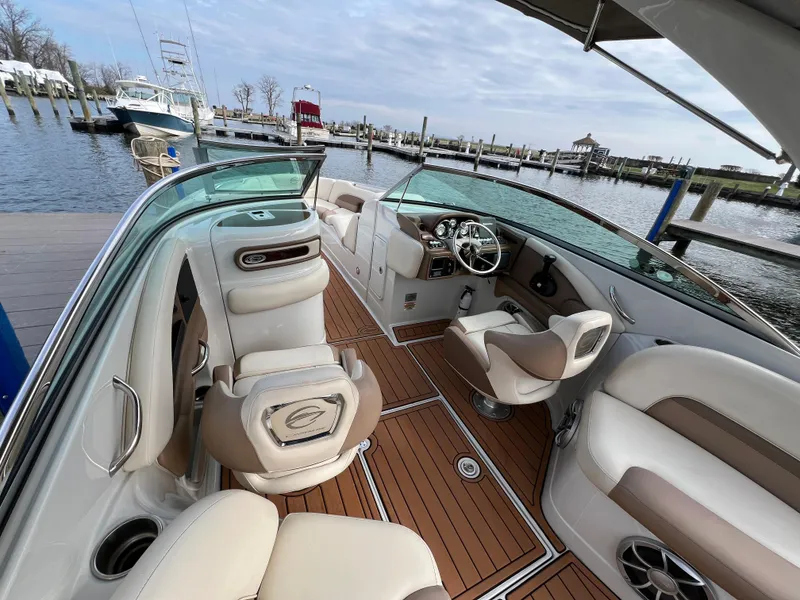Slide: The Image of 2016 Crownline 270 SS boat interior with luxurious seating and wood flooring at a marina. - 11