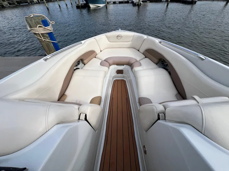Slide: The Image of 2016 Crownline 270 SS boat interior with white seating and wooden flooring at a dock. - 18