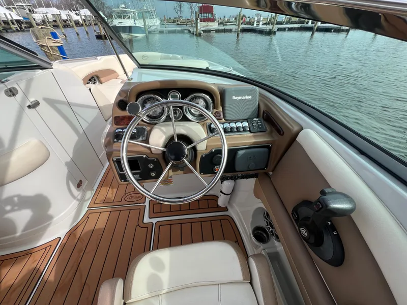 Slide: The Image of 2016 Crownline 270 SS boat cockpit with steering wheel and control panel, docked by the water. - 2