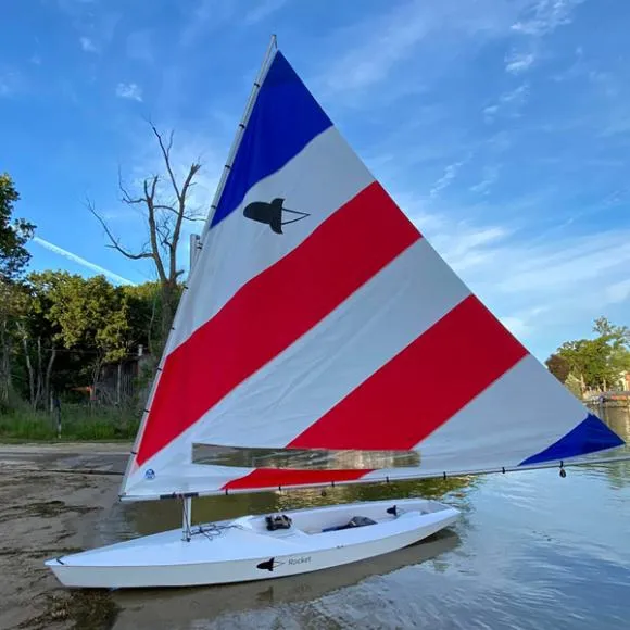 Slide: The Image of 2024 Fulcrum Speedworks Rocket sailboat with colorful sail on a calm lake. - 3