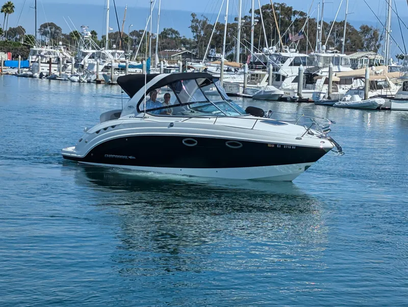 Slide: The Image of 2011 Chaparral Signature 270 boat cruising in a marina with other boats docked. - 16