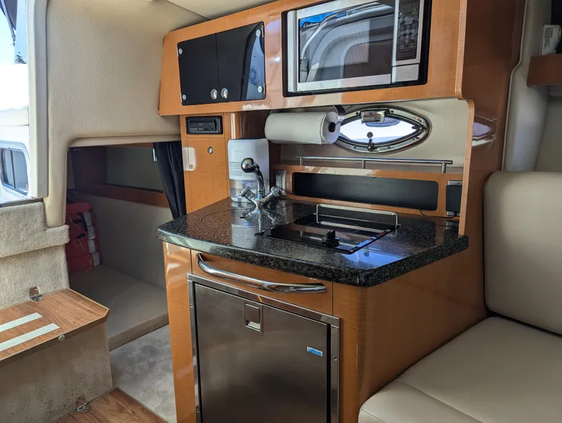 Slide: The Image of 2011 Chaparral Signature 270 interior kitchen with microwave, sink, and refrigerator. - 32