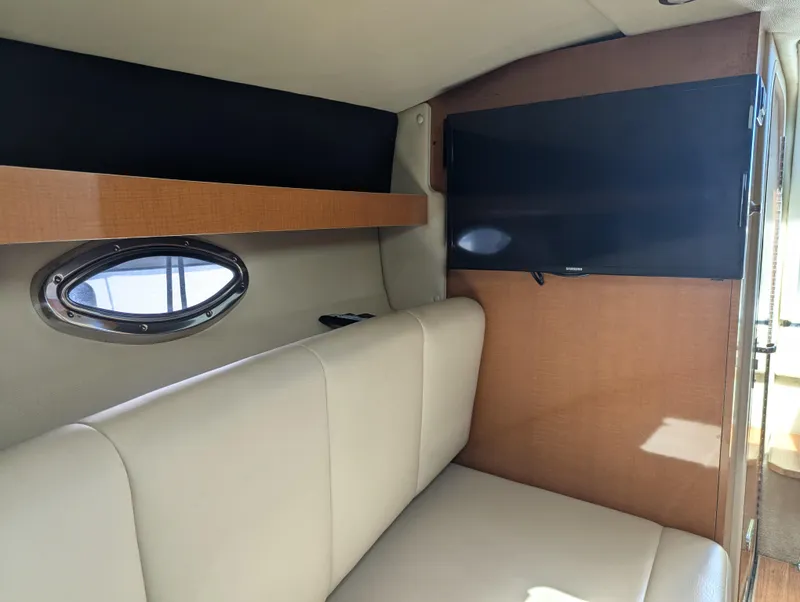 Slide: The Image of Interior of 2011 Chaparral Signature 270 with TV, porthole, and beige seating. - 35