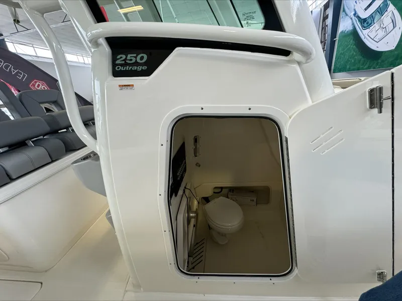 Slide: The Image of 2025 Boston Whaler 250 Outrage boat interior with open door revealing compact restroom. - 19