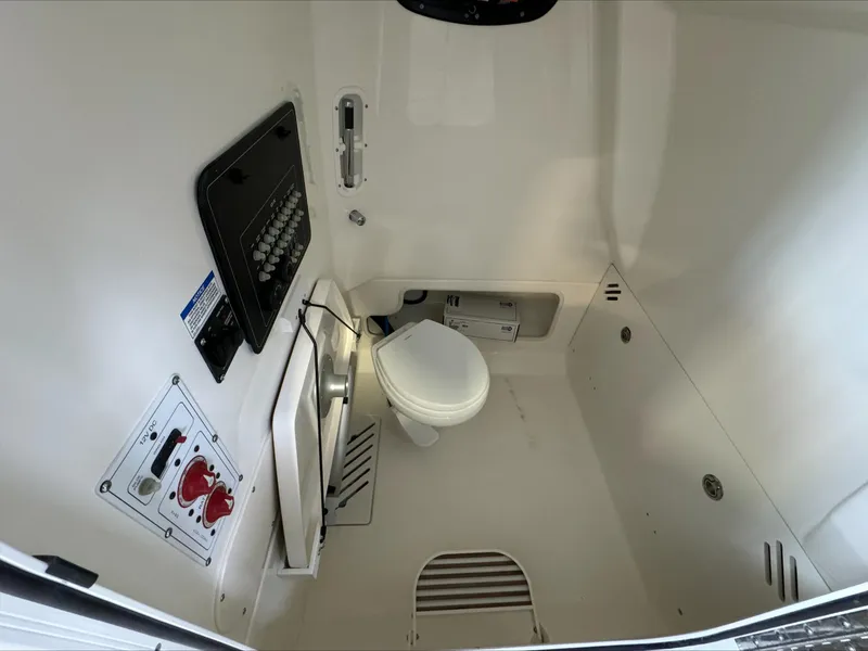 Slide: The Image of 2025 Boston Whaler 250 Outrage interior cabin with toilet and control panel. - 20