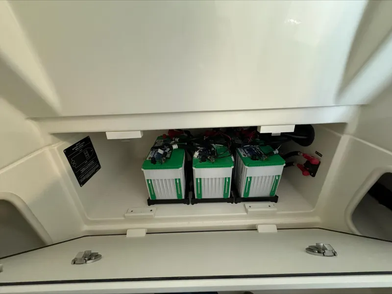 Slide: The Image of Battery compartment of 2025 Boston Whaler 250 Outrage boat, featuring three green batteries. - 23