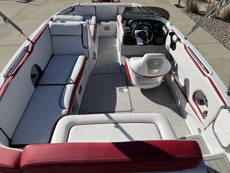 Slide: The Image of 2023 Crownline E205 XS boat interior with red and white seating, steering console, and spacious layout. - 6