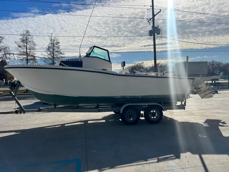 Slide: The Image of 1984 Dusky 233 boat on a trailer in a parking lot. - 5