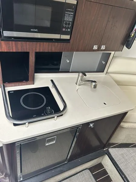 Slide: The Image of Compact kitchen area in a 2019 Monterey 295SY boat with stove, sink, and microwave. - 15