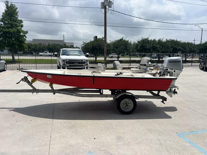Slide: The Image of Red Custom 14 boat (2023) on trailer with Honda outboard motor in parking lot. - 3