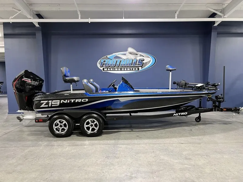 The Image of 2025 Nitro Z19 Pro boat in showroom, blue and black design, dual axle trailer. - 0