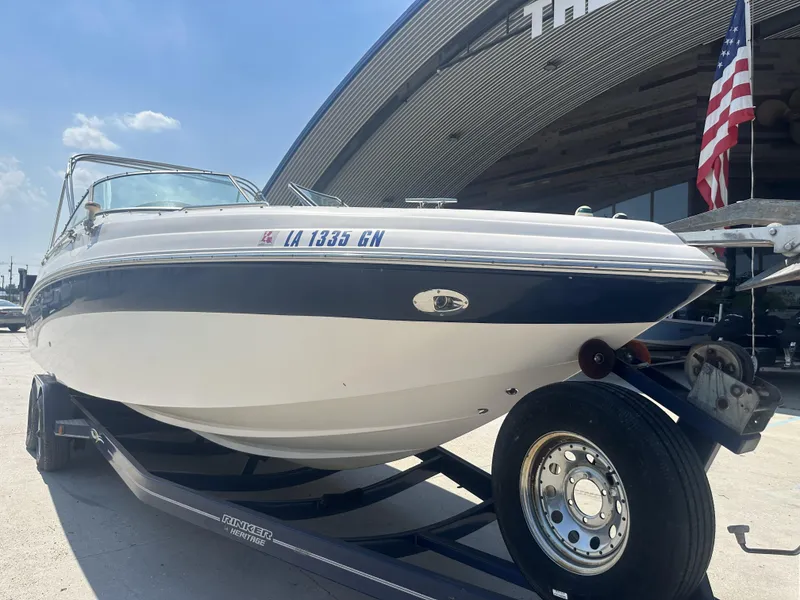 Slide: The Image of 2003 Rinker 282 Captiva boat on trailer, parked outside a building with an American flag. - 6