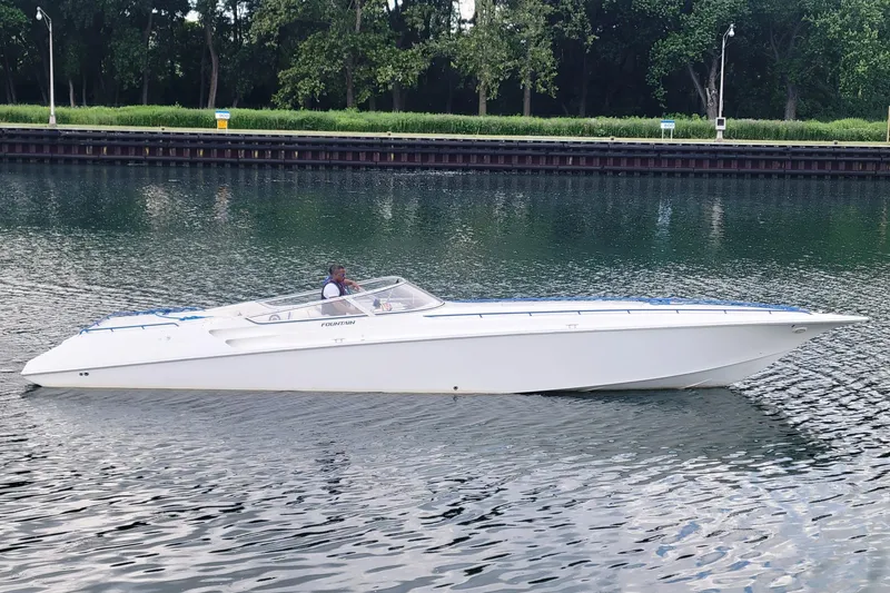 The Image of 1999 Fountain 42 Staggered speedboat cruising on a calm river with lush greenery. - 0