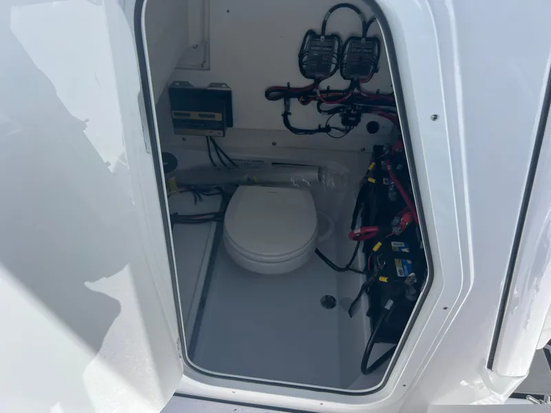 Slide: The Image of 2024 Sportsman Open 232 Center Console boat interior with marine toilet and electrical components. - 16